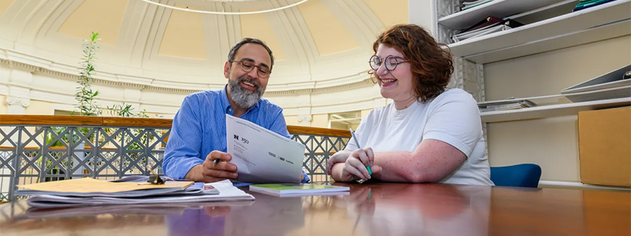 Two people sitting in the Jacobson Center discussing papers