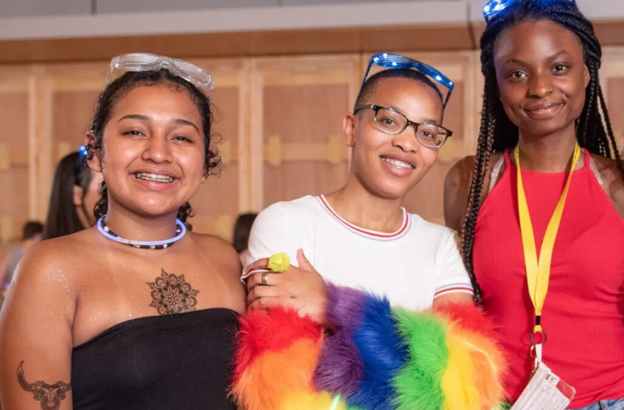 Three WGR students, smiling at the camera with glow-stick necklaces and glasses on.