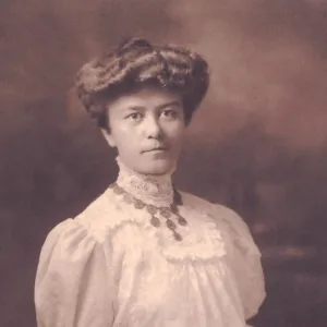 Antique photo of a woman sitting in a white dress with her hands on her lap