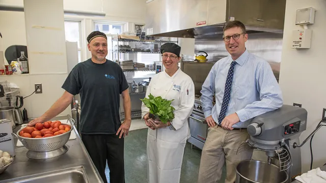 Andy Cox with two dining employees in one of the kitchens