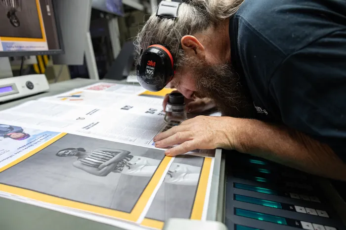 A man looks closely through a loupe at a printed page