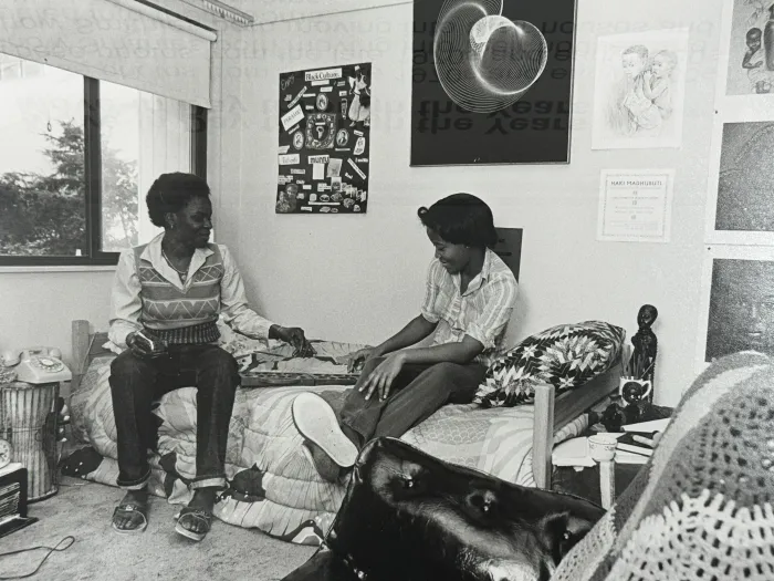 Two students sitting on bed in dorm room