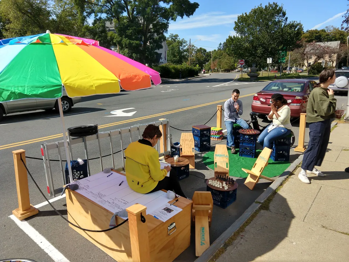 People relax in a portable park on the street, under an umbrella and surrounded by games